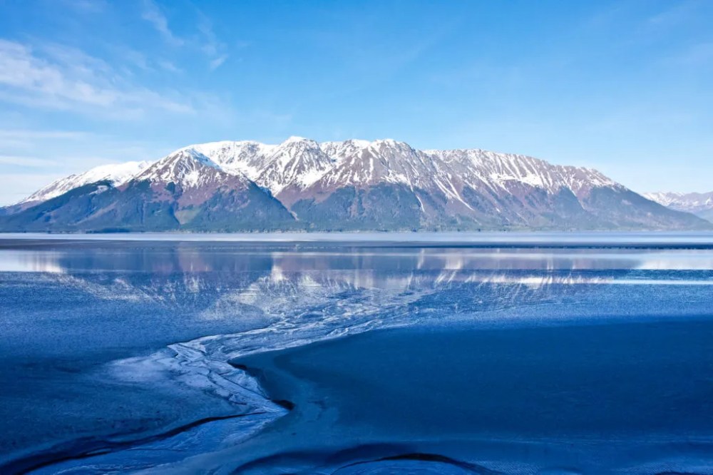 A mountain landscape reflects on the waters of Alaska’s Turnagain Arm ** Note: Slight graininess, best at smaller sizes